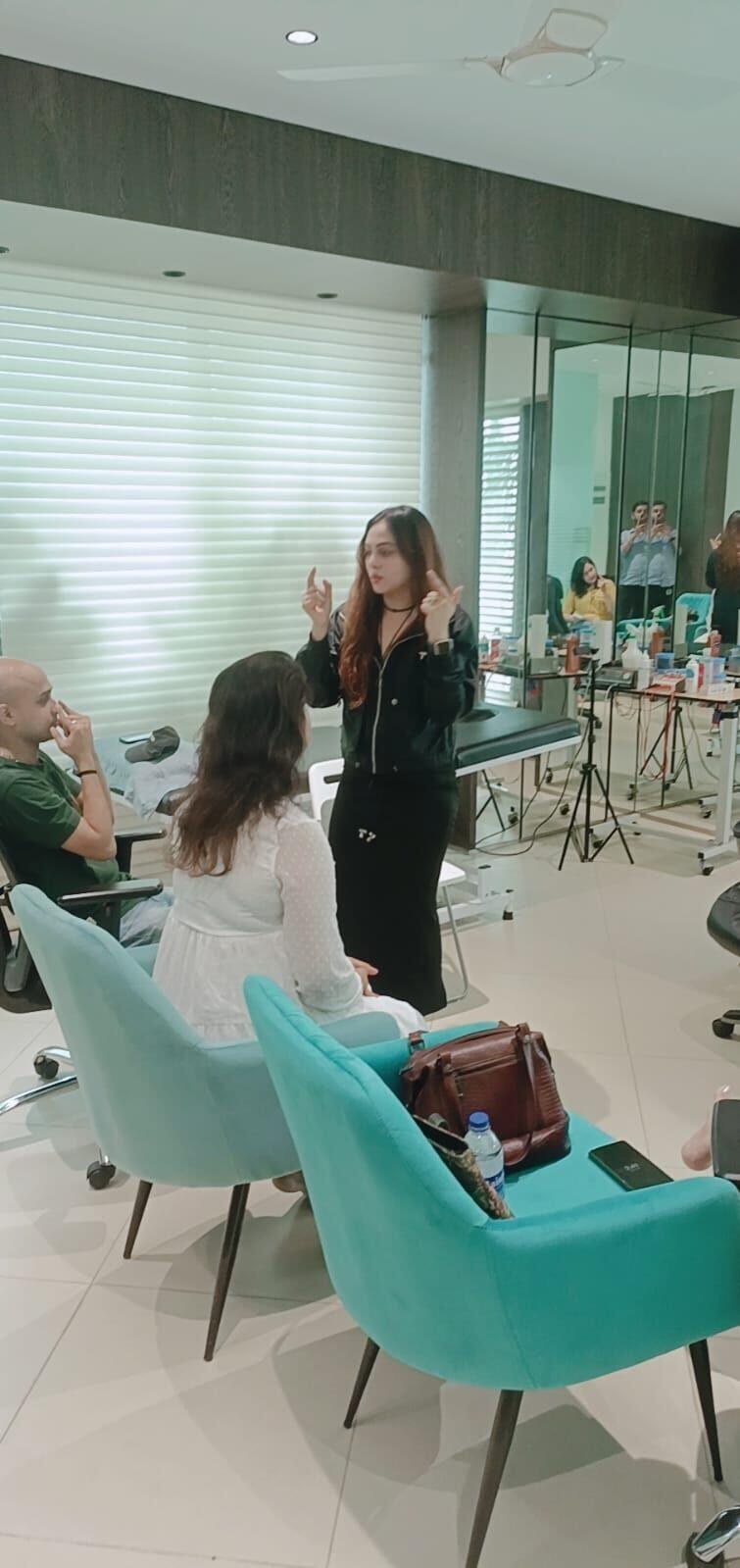 Vibha Jain standing and demonstrating a technique to a small group of three seated participants in a consulting room.