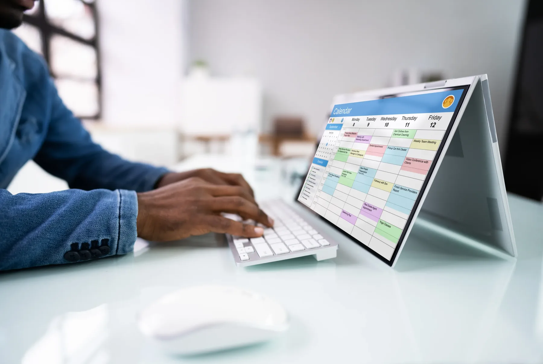 A person at a desk reviewing a weekly calendar on a laptop screen.